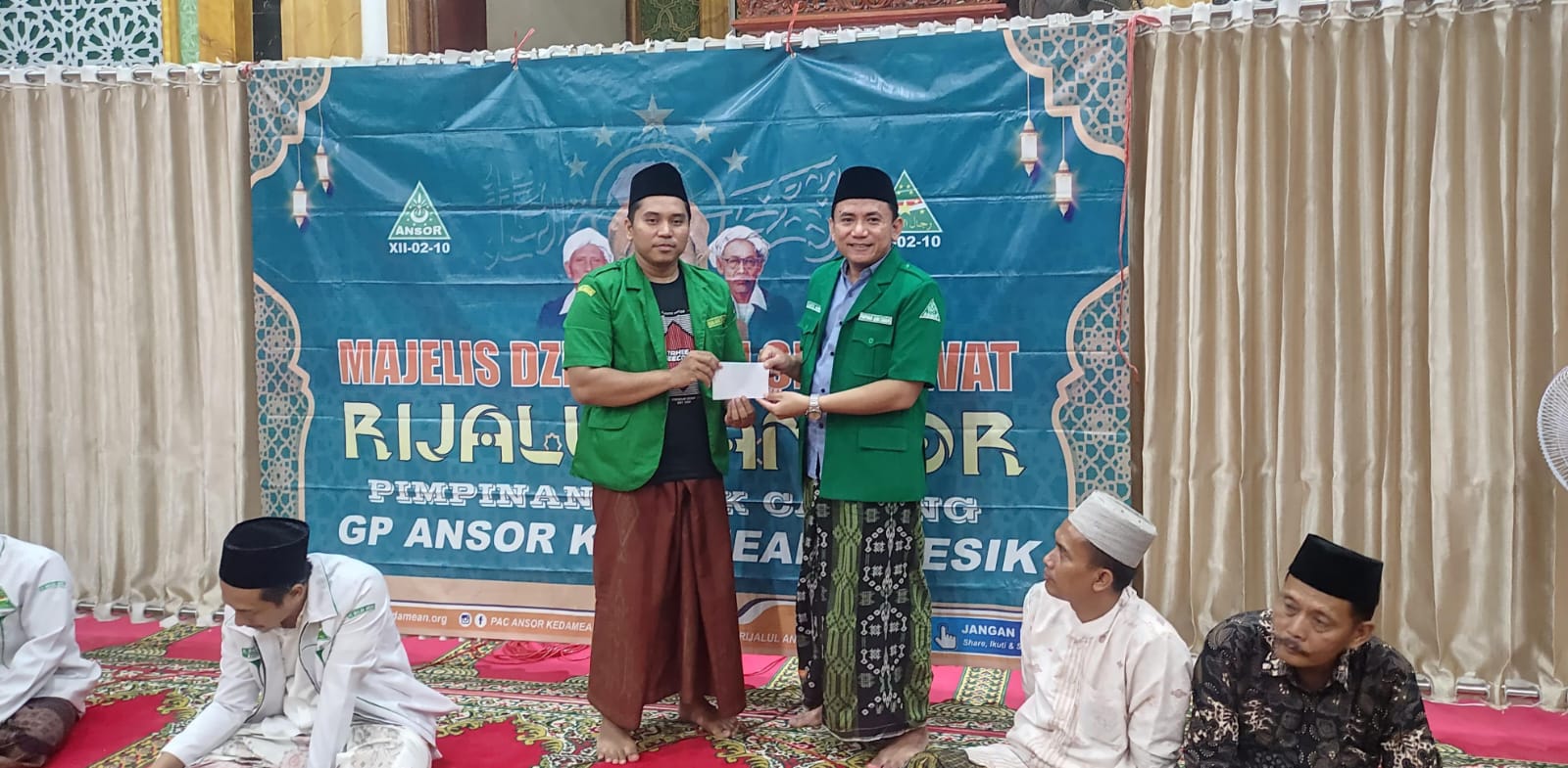 Ketua PAC GP Ansor Kedamean menyerahkan secara simbolis santunan kepada anak yatim, diserahterimakan kepada Ketua Pimpinan Ranting GP Ansor Turorejo. Foto: dok PAC GP Ansor Kedamean/NUGres
