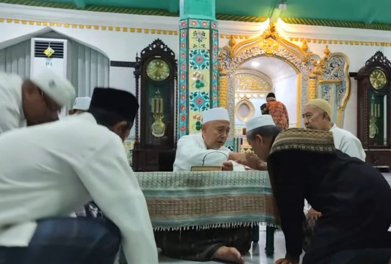 Pengajian ba'da subuh selalu ditutup dengan doa, para jamaah juga bermusafahah dengan Romo Kiai Farhan. Kesempatan ini tak jarang dari jamaah menyampaikan beberapa hal seperti meminta nasiha, hingga keluhan kepada sosok ulama sepuh Gresik yang juga Pj Rais Syuriyah PCNU Gresik tersebut. Foto: YouTube NUGres Channel/NUGres